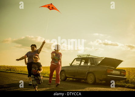 Kaukasische Familie Drachen auf Landstraße Stockfoto