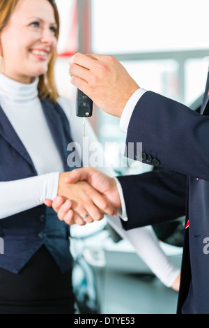 Verkäufer oder Auto-Verkäufer und Kunde im Autohaus, sie Hände schütteln, übergibt die Autoschlüssel Stockfoto