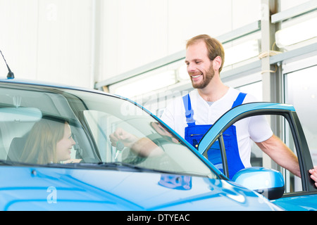 Kundin und Mechaniker in der Werkstatt oder MOT mit Auto für Service-Inspektion Stockfoto