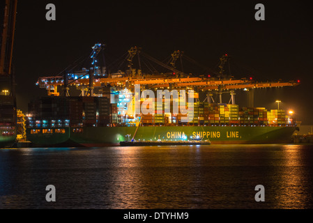 ein Schiff mit Containern unter großen Kräne an der Pier im Hafen von Rotterdam bei Nacht Stockfoto
