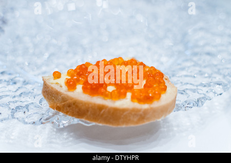 Sandwich mit Lachs rot Kaviar auf einer transparenten Glasplatte auf weiß Stockfoto