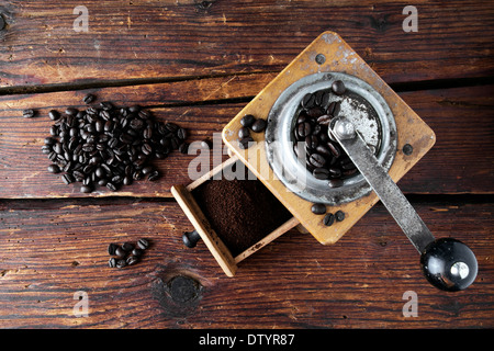 Alte Kaffeemühle mit Kaffeebohnen auf eine Holzoberfläche Stockfoto