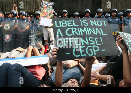 Manila, Philippinen. 25. Februar 2014. Demonstranten liegen auf dem Boden vor der Edsa-Schrein, während bei der schwarzen Dienstag Demonstration von der Polizei in Quezon Stadt bewacht wird. --Verschiedene Mediengruppen, zusammen mit Studentenaktivisten, gedachte der 28. Jahrestag der Edsa Revolution mit einer Protestkundgebung gegen die Cybercrime Law. Bildnachweis: J Gerard Seguia/NurPhoto/ZUMAPRESS.com/Alamy Live-Nachrichten Stockfoto