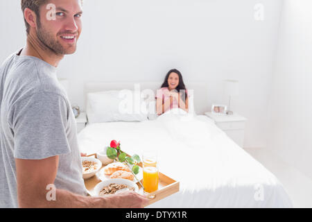 Gut aussehender Mann seiner Frau das Frühstück bringen Stockfoto