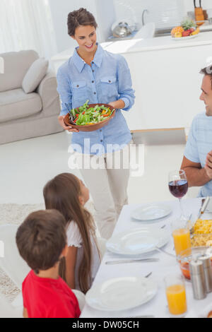 Frau bringt einen Salat zu ihrer Familie Stockfoto