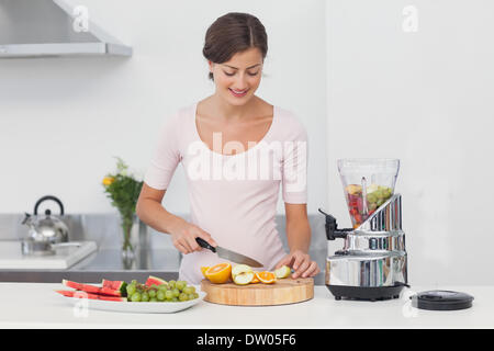 Schwangere Frau Schneiden von Früchten in der Küche Stockfoto