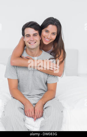 Frau umarmt ihr Partner im Bett saß Stockfoto