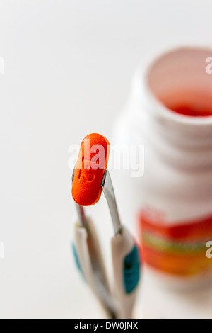 Eine generische Marke Ibuprofen Tablet mit Flasche per Pinzette daran gehalten Stockfoto