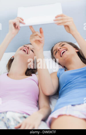 Mädchen im Bett halten tablet Stockfoto