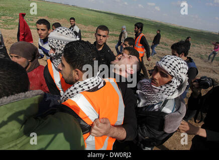 Gaza-Stadt, Gaza-Streifen. 25. Februar 2014. Palästinenser tragen einen verletzten Mann bei Zusammenstößen mit israelischen Sicherheitskräften in der Nähe von Nahal Oz Grenzübergang mit Israel nach einer Demonstration zum Gedenken an die Ibrahimi-Moschee-Massakers von 1994 in Hebron. Jüdische Extremisten Baruch Goldstein getötet 29 palästinensischen Gläubigen an der Ibrahimi-Moschee, das Grab der Patriarchen, in der Westbank-Stadt am 25. Februar 1994 von Juden genannt. © Ashraf Amra/APA Images/ZUMAPRESS.com/Alamy Live-Nachrichten Stockfoto