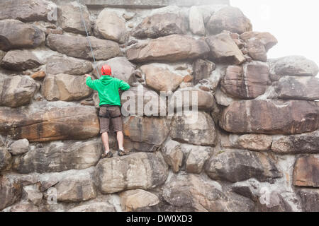 Entschlossenen Mann Skalierung einer großen Felswand Stockfoto
