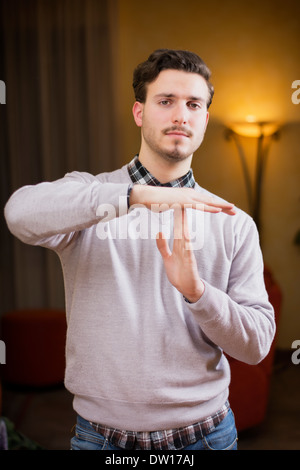 Attraktive junge Mann tut Timeout Zeichen, indoor erschossen in einem Haus Stockfoto