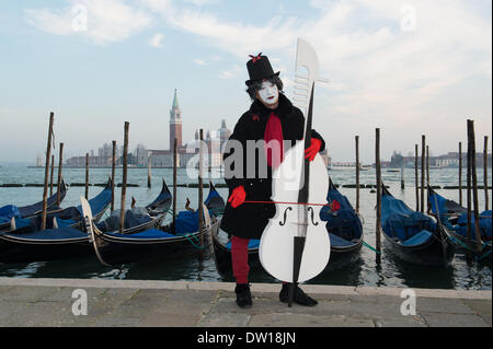 Venedig, Italien. 25. Februar 2014. Ein männlicher Mime spielt eine große Cello mit einem Wirbelkasten und blättern geformt wie die Vorderseite einer Gondel, die auch im Hintergrund vorhanden sind. Venedig Karneval - Dienstag, 25. Februar. Bildnachweis: MeonStock/Alamy Live-Nachrichten Stockfoto