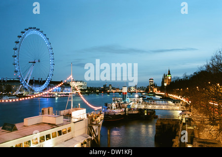 London und die Themse beleuchtet in der Dämmerung, im Winter, mit Blick nach Westen in Richtung Westminster von Victoria Embankment Stockfoto