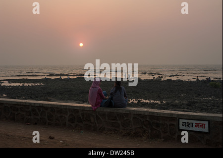 Zwei Damen im Chat, wie die Sonnenuntergänge an der Musikpavillon in Bandra, Mumbai, Indien Promenade Stockfoto