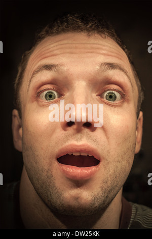 Junge schockiert kaukasischen Mann Closeup Portrait auf dunklem Hintergrund Stockfoto