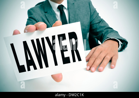 ein Mann in einem Anzug sitzt in einem Schreibtisch hält ein Schild mit dem Wort Anwalt geschrieben Stockfoto