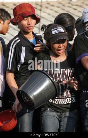 Eine junge Frau hält einen Eimer, wie sie bereitet, Wasser während einer laotischen Neujahrsfest in Luang Prabang, Laos zu werfen. Stockfoto