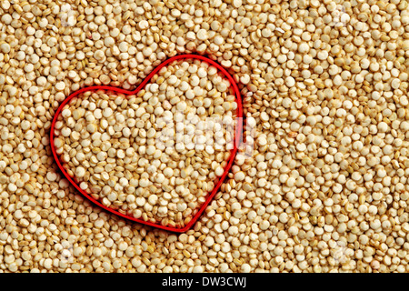 Rotes Herzform auf rohem Quinoa Hintergrund Stockfoto