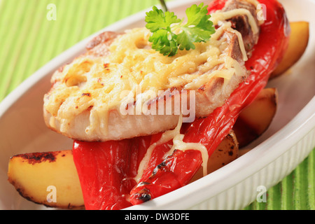 Schweinekotelett, garniert mit geriebenem Käse, serviert mit gerösteten Kartoffeln und Paprika Stockfoto