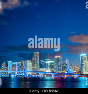Miami, Florida, beleuchtet Sonnenuntergang mit bunten, Geschäfts-und Wohngebäuden und Brücke an der Biscayne Bay Stockfoto