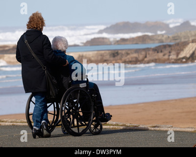 Frau im Rollstuhl und Helfer Blick auf das Meer, Bude, Cornwall, UK Stockfoto