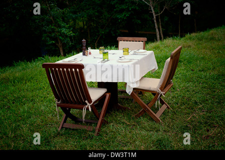 Dining Al Fresco - ein Abendessen-Einstellung für drei 3 im Freien in der ugandischen Abend. Stockfoto