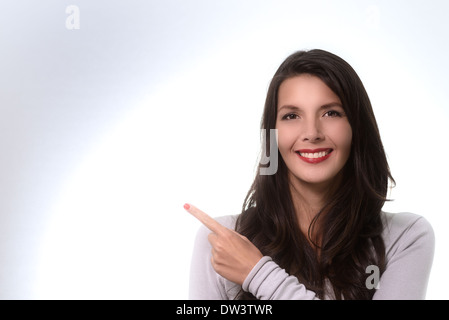 Schöne stilvolle Frau zeigte um Raum mit einem freundlichen Lächeln zu kopieren, wie sie Ihre Aufmerksamkeit auf Ihren Text oder Ihre Anzeige zieht Stockfoto