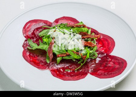 Weichkäse mit in Scheiben geschnittenen rote Beete, Sonne getrockneten Tomaten und Rucolasalat garniert mit Sprossen Stockfoto
