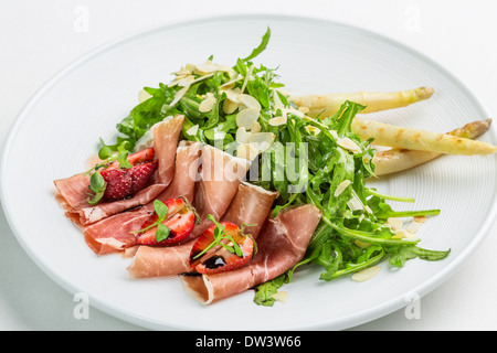 Parmaschinken mit Erdbeeren auf Rucola-Salat mit Mandelblättchen und Spargel Stockfoto