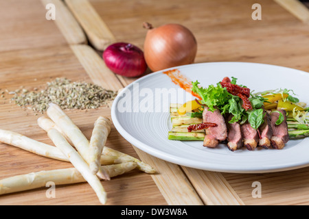 Schweinefleisch auf einem Bett aus Spargel mit Sonne getrockneten Tomaten-Salat Stockfoto