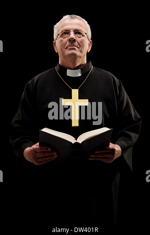 Katholische Pfarrer hält eine Bibel und beten Stockfoto