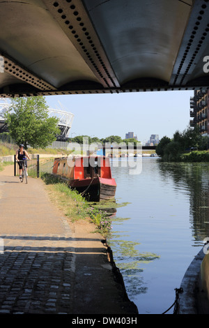 Radfahren entlang Lee Flussschifffahrt auf trendige Hackney Wick, East London, UK, die Queen Elizabeth Olympiastadion hinter Stockfoto
