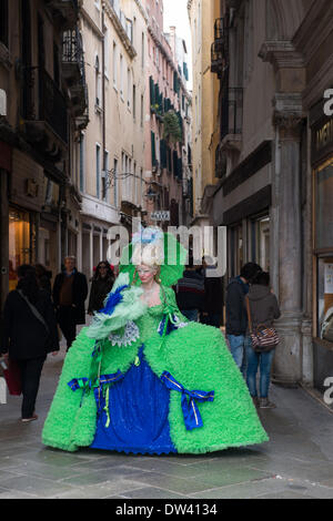 Venedig, Italien. 26. Februar 2014. Mit eine Kulisse eines Venedigs Gassen nur von San Marco (Markusplatz entfernt) diese Dame in ihrem herrlichen grünen und blauen Kleid mit Gondel stellt Spitze Perücke. Venedig Karneval - Mittwoch, 26. Februar. Bildnachweis: MeonStock/Alamy Live-Nachrichten Stockfoto