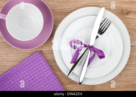 Gabel mit Messer über Teller, Kaffeetasse und Serviette. Auf Holztisch Hintergrund mit Textfreiraum Stockfoto