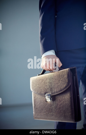 Vertikal abgeschnitten Bild eines Kaufmanns trägt eine Leder-Aktentasche isoliert auf grau Stockfoto