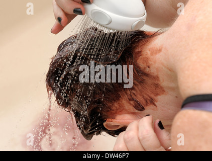 Frau, die Haare färben über eine Badewanne mit einem Duschkopf spülen Stockfoto