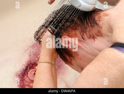 Frau, die Haare färben über eine Badewanne mit einem Duschkopf spülen Stockfoto