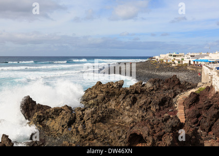 Raue See mit Wellen an Lavafelsen entlang der zerklüfteten Küste im kleinen Resort von El Golfo, Lanzarote, Kanarische Inseln, Spanien Stockfoto