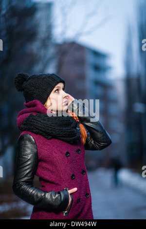 Attraktive Frau tragen Wintermantel, Stadt Abend auf Hintergrund, Vordergrund im Fokus Stockfoto