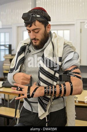 Religiösen jüdischen jungen Mann anziehen Gebetsriemen - Drang - am Morgen-Services bei der Ohel in Cambria Heights, Queens, NY Stockfoto