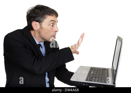 Geschäftsmann, einen Zauberspruch auf seinem Laptop halten es in der Hand beim gestikulieren mit der gespreizten Hand auf den Bildschirm Stockfoto