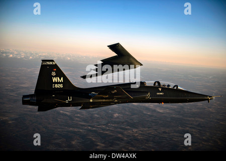 Ein Flugzeug der US Air Force t-38 Talon begleitet ein b-2 Spirit Stealth Bomber Flugzeug wie sie Whiteman Air Force Base 20. Februar 2014 in Drehknopf Noster, MO. überfliegen Stockfoto