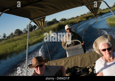 Touristen genießen die letzten Sonnenstrahlen auf dem Wasser-Safari-Camp hergestellt aus Eagle Island Camp von Orient-Express, außerhalb Stockfoto