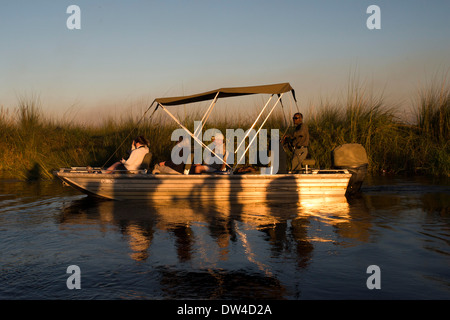 Touristen genießen die letzten Sonnenstrahlen auf dem Wasser-Safari-Camp hergestellt aus Eagle Island Camp von Orient-Express, außerhalb Stockfoto