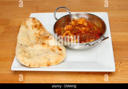 Chickencurry mit Naan-Brot auf einem Teller auf einem Holztisch Stockfoto