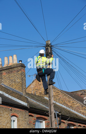 Telekommunikation Ingenieur arbeitet auf eine obenliegende Telefonmast Kommunikation unter Reihenhäuser in London, Großbritannien Stockfoto
