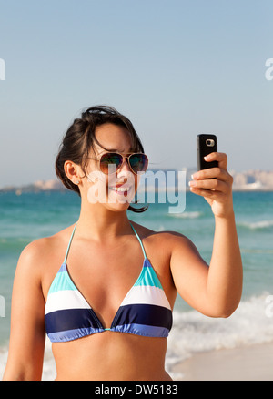 Frau fotografieren Selfie am Strand im Bikini, im Urlaub, Jumeirah Beach, Dubai, Vereinigte Arabische Emirate, Vereinigte Arabische Emirate, Naher Osten Stockfoto