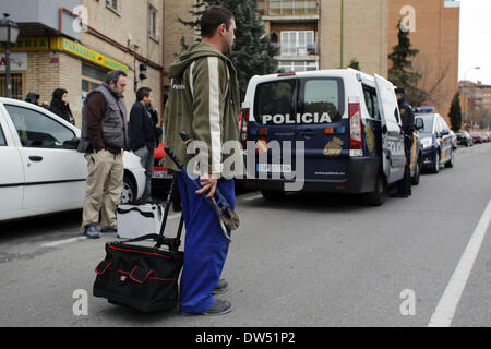 Madrid, Spanien. 27. Februar 2014. Polizei Wache stehen, richtig, da eine Schlosser verlässt mit einem Bolzenschneider und ein Brecheisen als Gehäuse Menschenrechtsaktivisten zwingen die Verschiebung der Carolina Salazar Fernandez Räumung in Madrid, Spanien, Donnerstag, 27. Februar 2014. Carolina Salazar Fernandez, 23 Jahre alt, ist eine alleinerziehende Mutter von zwei Kindern: Jesus, 3 Jahre alt, und Abraham, 6 Jahre alt. Ihr einziges Einkommen, ist es ein Staat nutzen von 530 Euro ($ 723). Sie hat eine leere abgeschotteten Wohnung Besitz SAREB Bank im Februar 2013 besetzt. Sie versucht zu verhandeln, um eine niedrige geschützten Miete, da ihr Einkommen zahlen ist es nicht Stockfoto