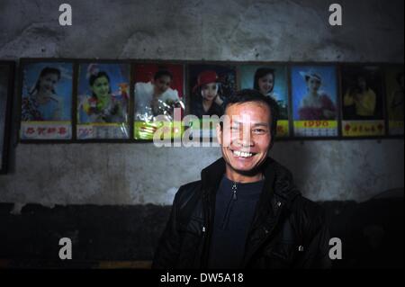 (140228)--RONG'AN, 28. Februar 2014 (Xinhua)--Dorfbewohner Mo Shihe ist mit alten Plakate aufhängen an der Wand in Tongban Dorf, Rong'an County, South China Autonome Region Guangxi Zhuang, 22. Februar 2014 in seinem Haus zu sehen. Vierzig-sechs-Jahr-alten langen Gexiong wurde im Dorf Tongban, einem kleinen Dorf weit weg in den Berggebieten der Guangxi Zhuang autonomen Region geboren. Vor etwa zwanzig Jahren ließ lange verließ die Heimatstadt für Arbeit ebenso wie viele seiner Generation entschieden zu tun, sein Vater allein zu Hause. Als immer mehr jungen Menschen aus der Heimatstadt ging, das einst lebendige Dorf war auf den Stockfoto